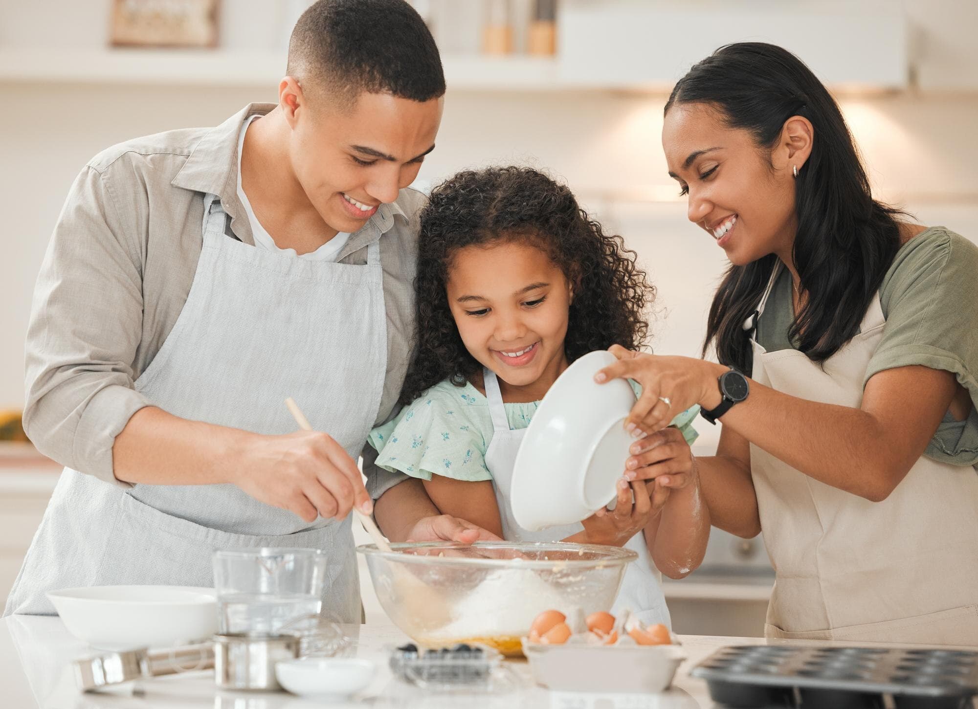 Padres e hija cocinando juntos, enseñando tradiciones familiares